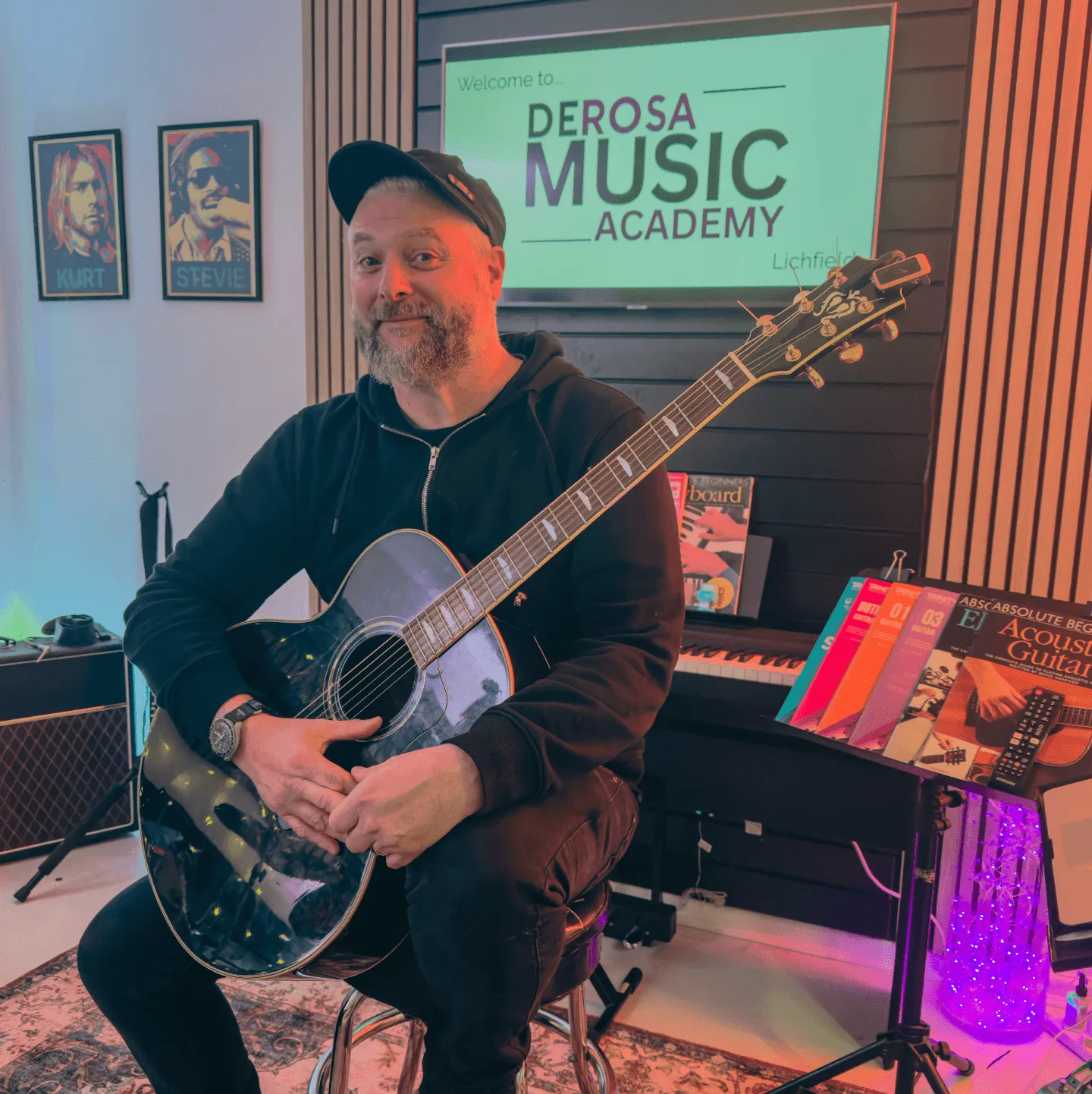 Bren, founder and lead tutor at Derosa Music Lichfield, holding a guitar
